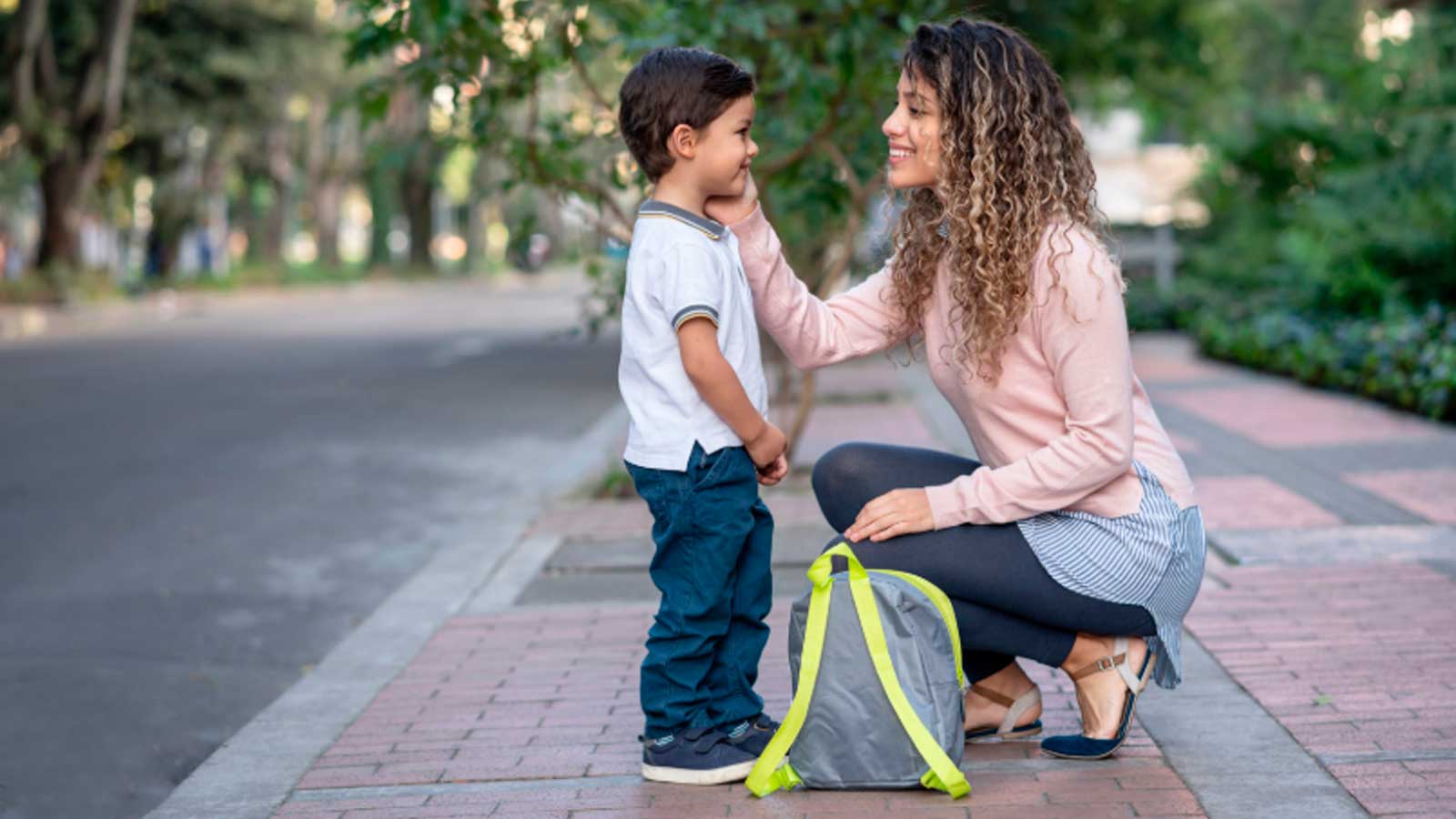 Madre junto a su hijo pequeño con una mochila escolar antes de ir al colegio
