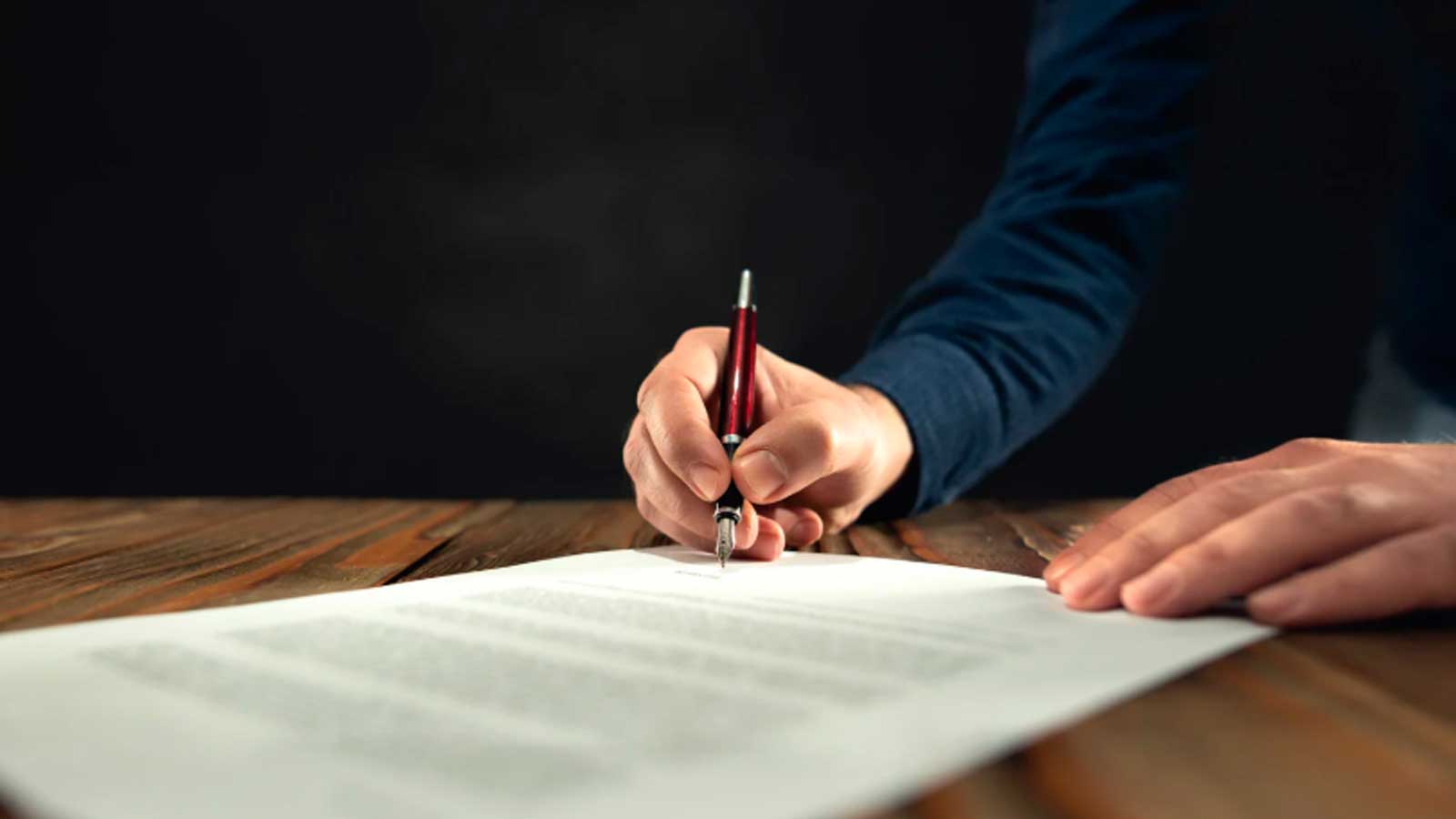 Una persona firma un documento para ilustrar la cancelación de una pareja de hecho en Madrid mediante representante.