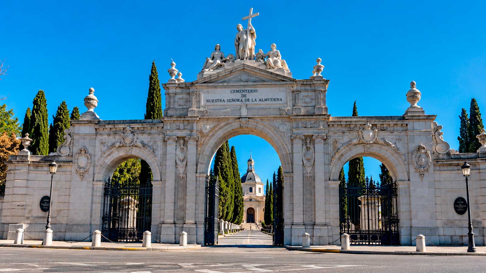 Entrada principal del Cementerio de la Almudena de Madrid, con sus tres arcos monumentales y la capilla al fondo.