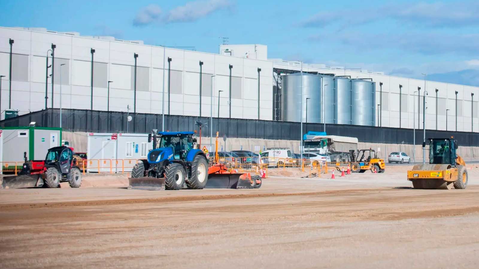 Obras junto a un gran centro de datos con maquinaria pesada y equipos industriales en el exterior.