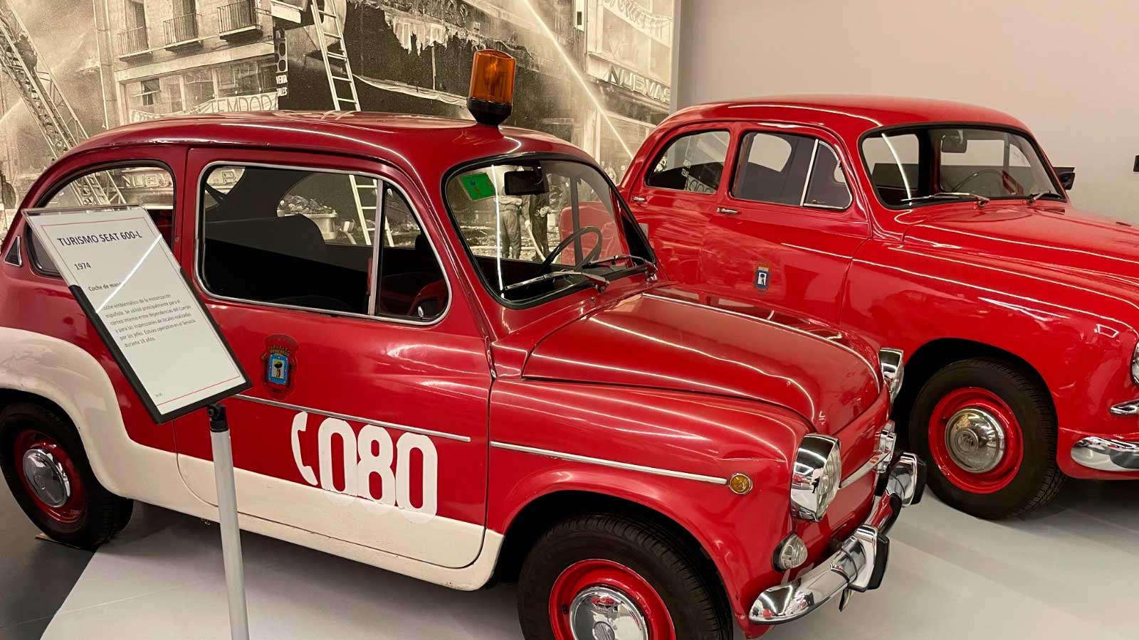 Dos coches antiguos rojos, incluido un SEAT 600, expuestos en el Museo de Bomberos de Madrid, en Puente de Vallecas.