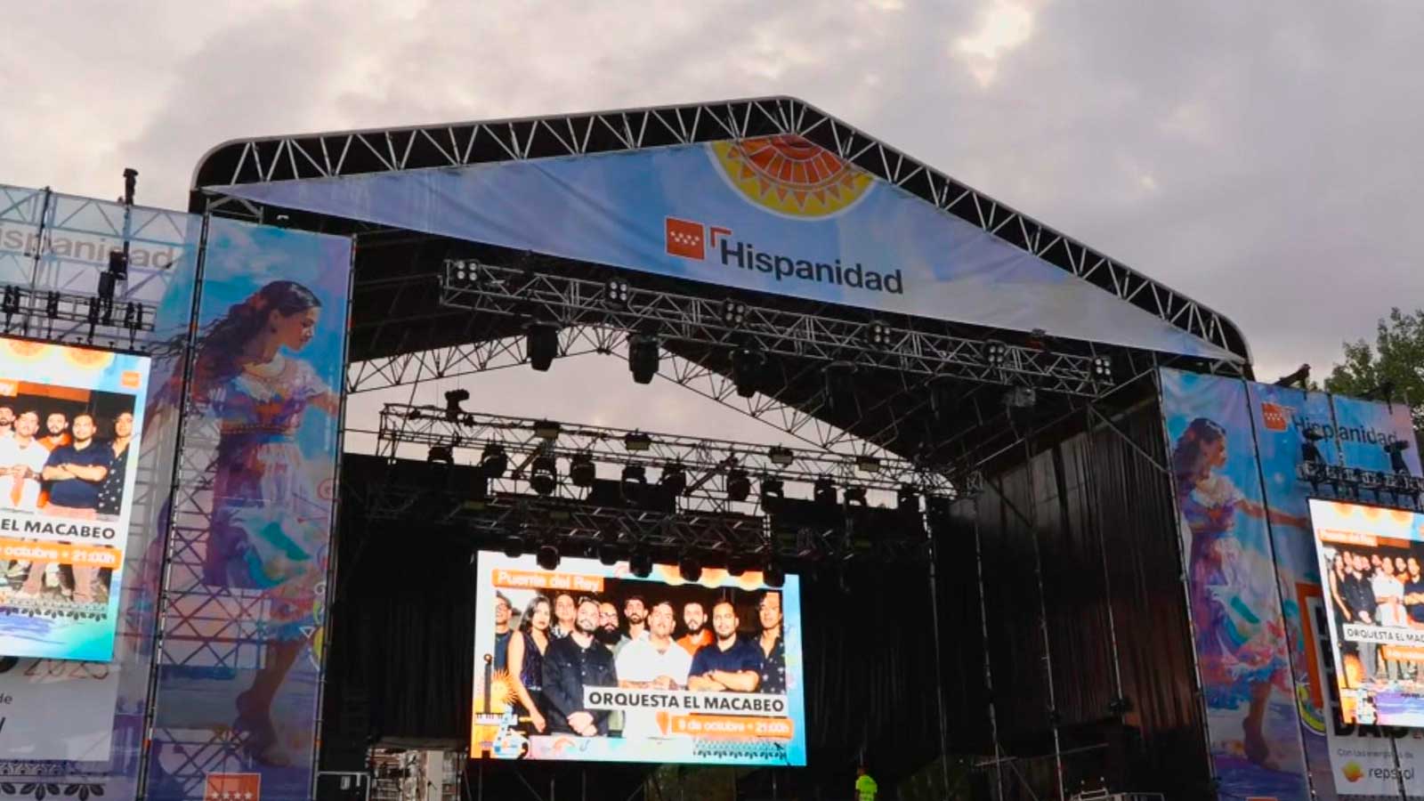 Escenario de los conciertos gratuitos de la Hispanidad en Madrid, con pantallas y carteles del festival.