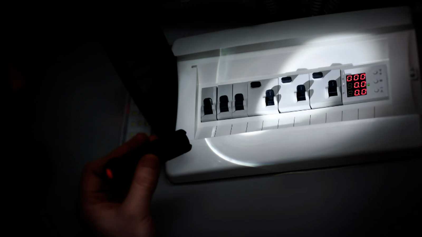 Cuadro eléctrico iluminado con una linterna durante un corte de luz en una vivienda