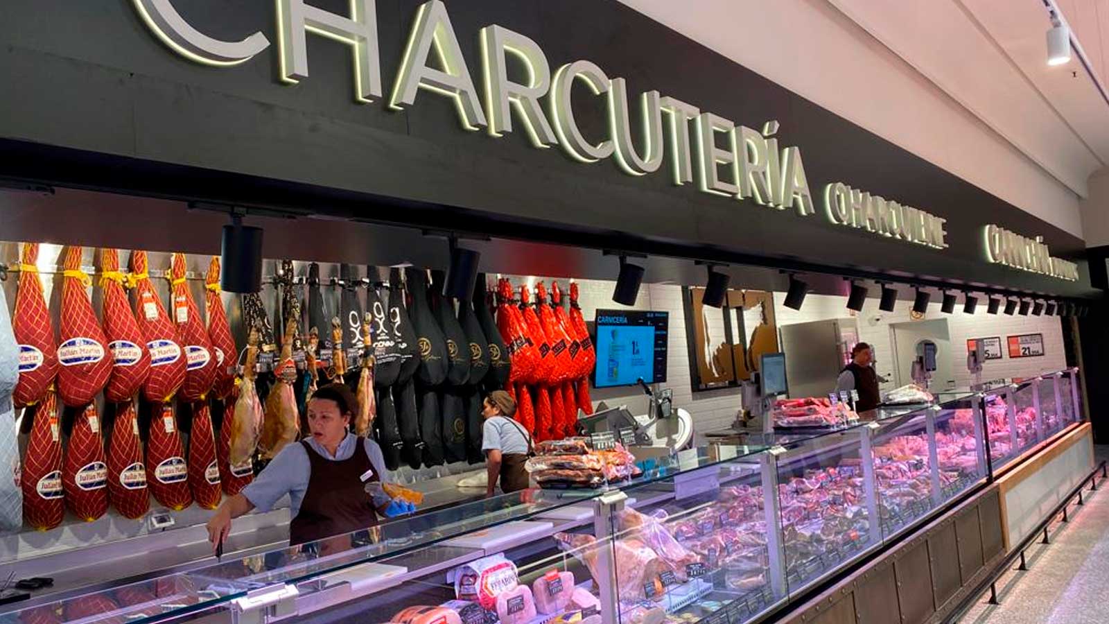 Empleados trabajando en la sección de charcutería de El Corte Inglés, donde se ofrecen cursos gratuitos con opción a contrato indefinido.