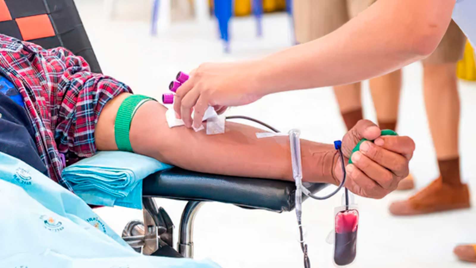 Una persona dona sangre mientras una sanitaria realiza la extracción en un centro de donación.