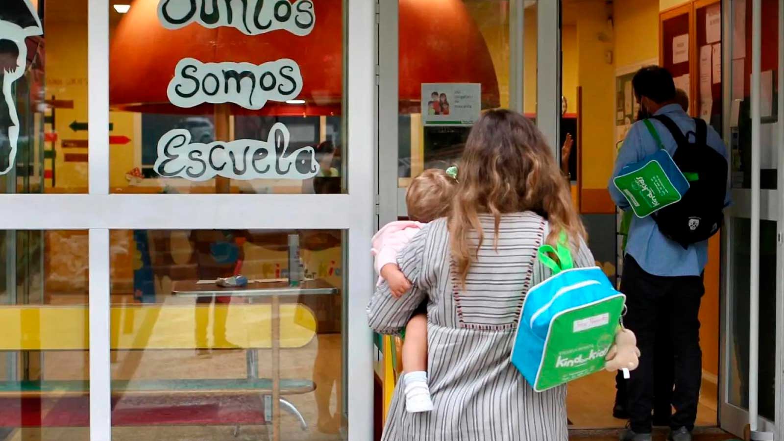 Madre con su hija en brazos entrando en una escuela infantil de Madrid.