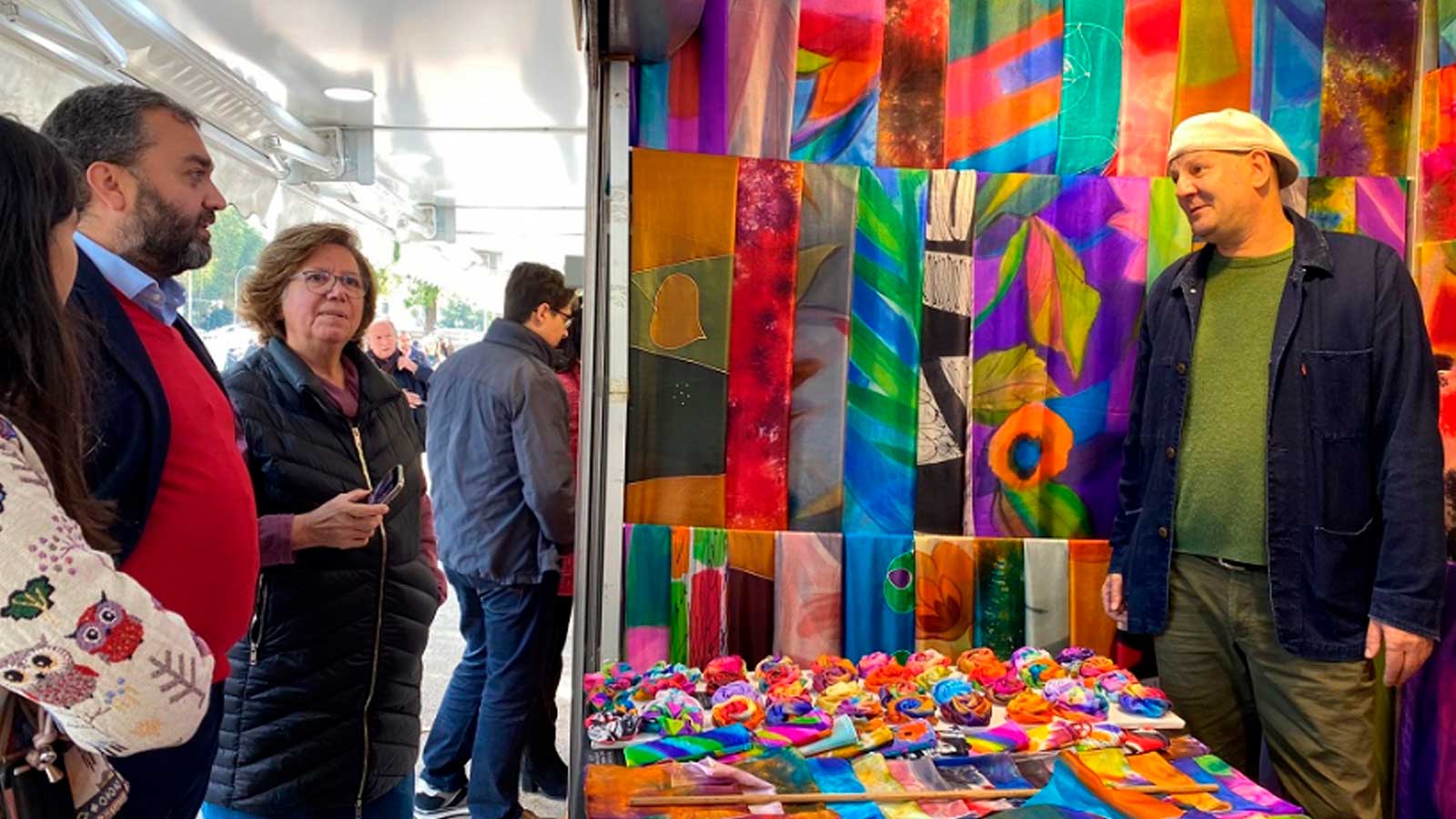 Visitantes observan productos textiles artesanales en un puesto de la Feria de Artesanía de Otoño de Madrid.