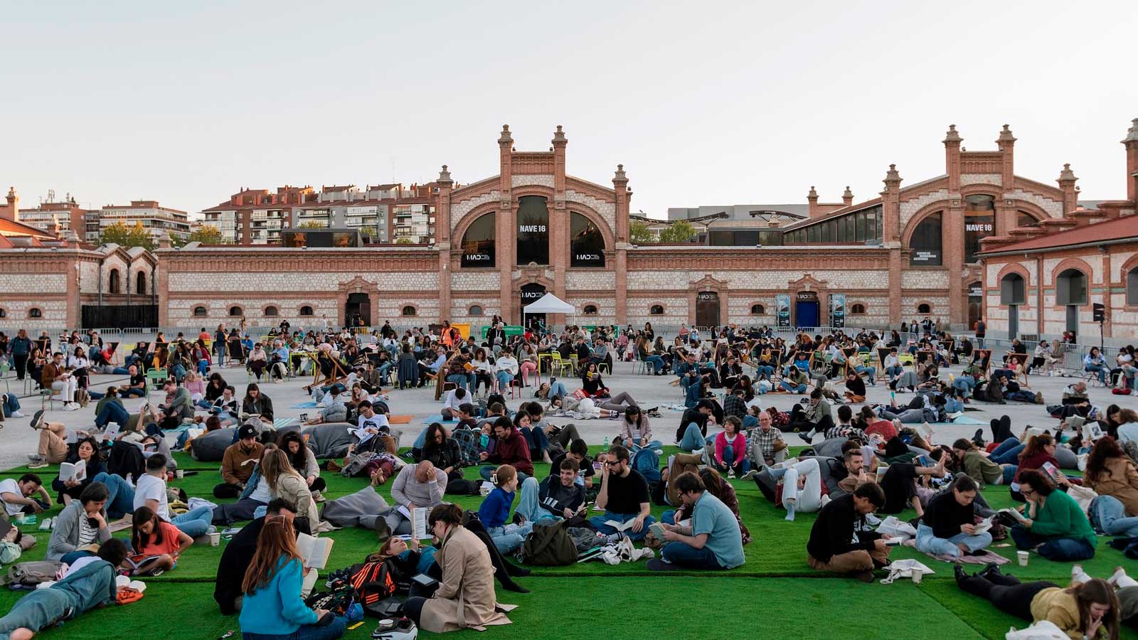 Decenas de personas leen libros al aire libre en Matadero Madrid durante una actividad cultural dedicada a la lectura.