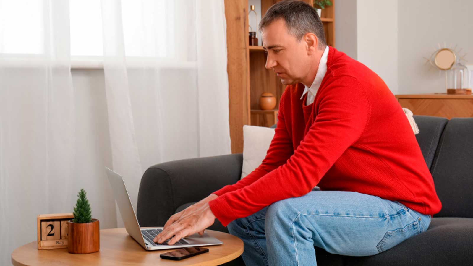 Hombre utilizando un ordenador portátil desde casa para realizar trámites relacionados con Hacienda.