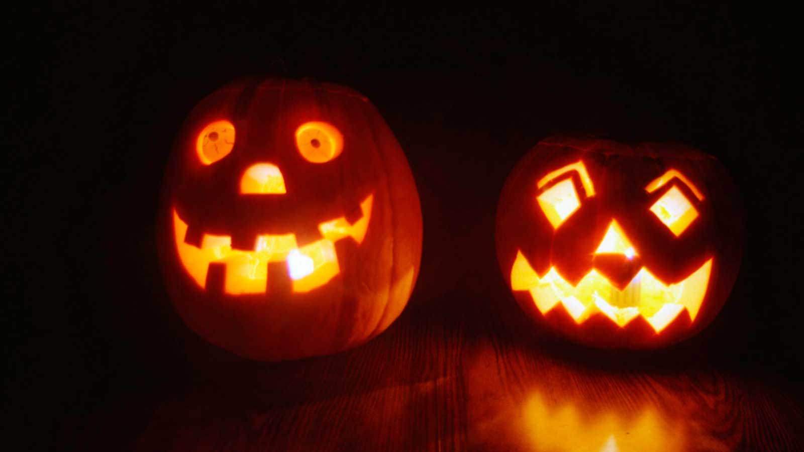 Calabazas de Halloween con una vela encendida junto a decoraciones en una vivienda.