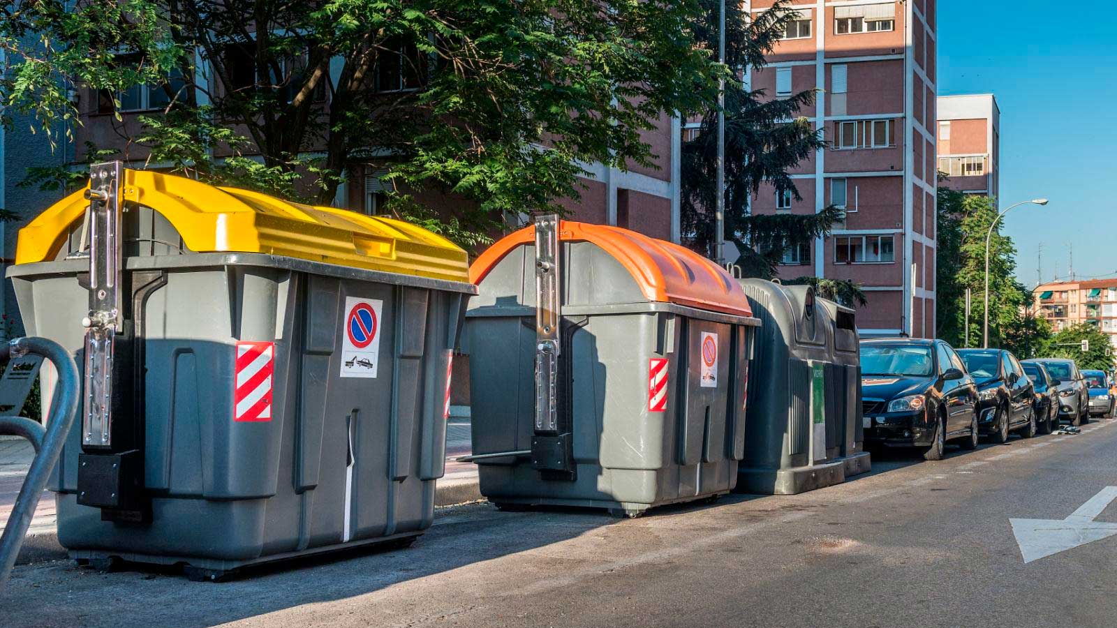 Contenedores de basura junto a edificios residenciales de Madrid, donde se prepara una rebaja del IBI para 2027.