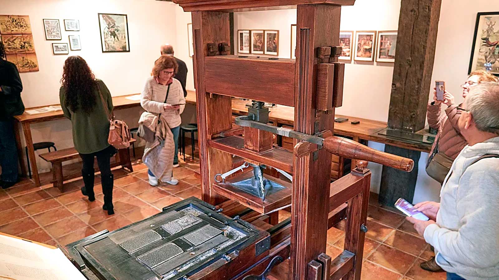 Visitantes junto a una prensa de madera en la imprenta de El Quijote de Madrid