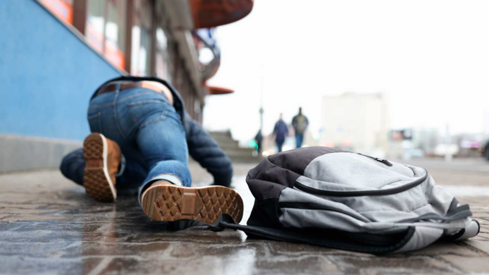 Persona caída en una acera junto a una mochila, imagen ilustrativa de una posible reclamación por daños en Madrid.