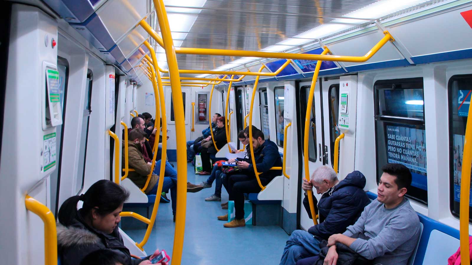 Interior de un tren de la Línea 1 de Metro de Madrid con varios viajeros sentados durante un trayecto.