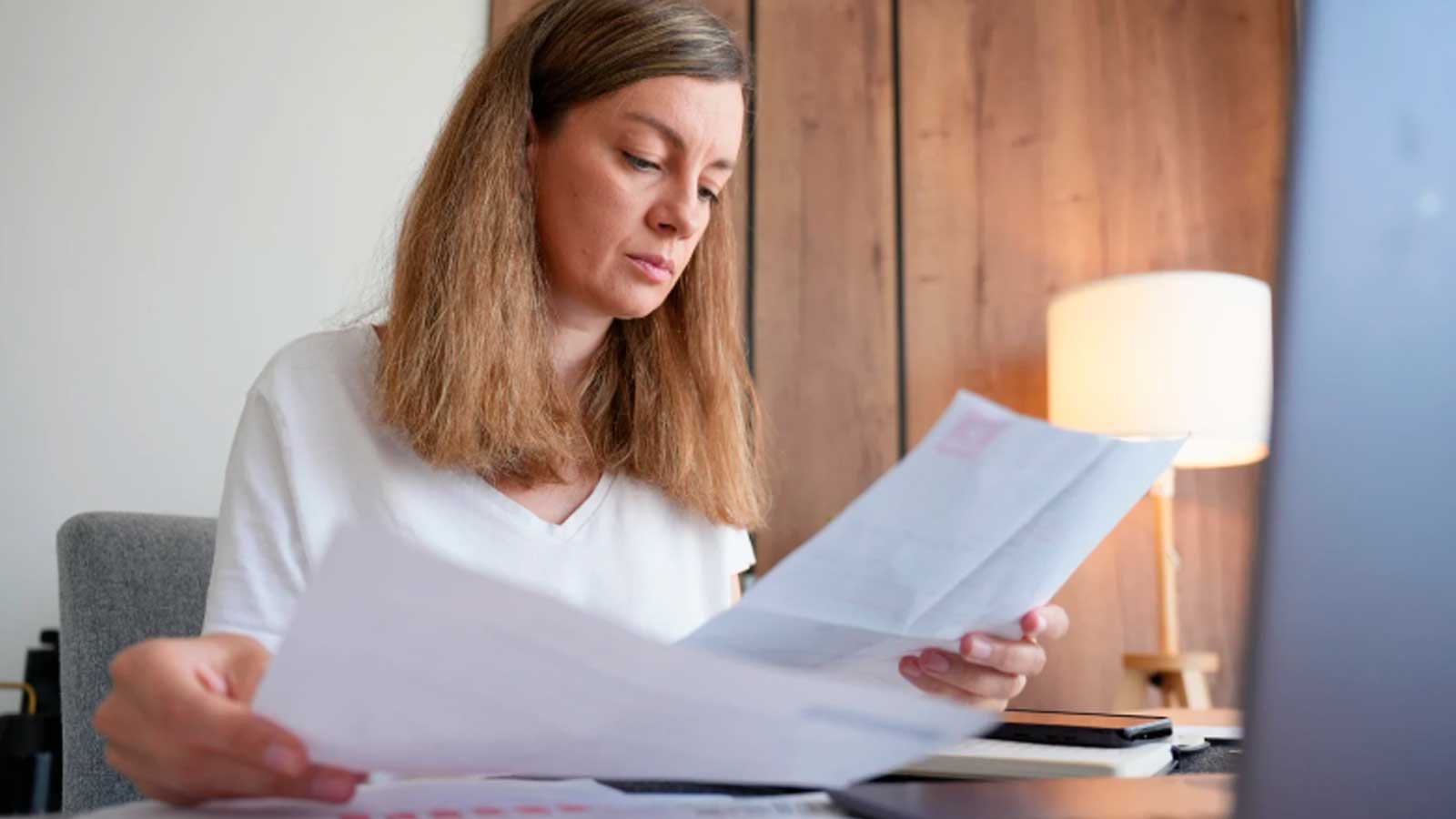 Mujer revisando documentos relacionados con una baja laboral y el pago directo de la incapacidad temporal en Madrid.
