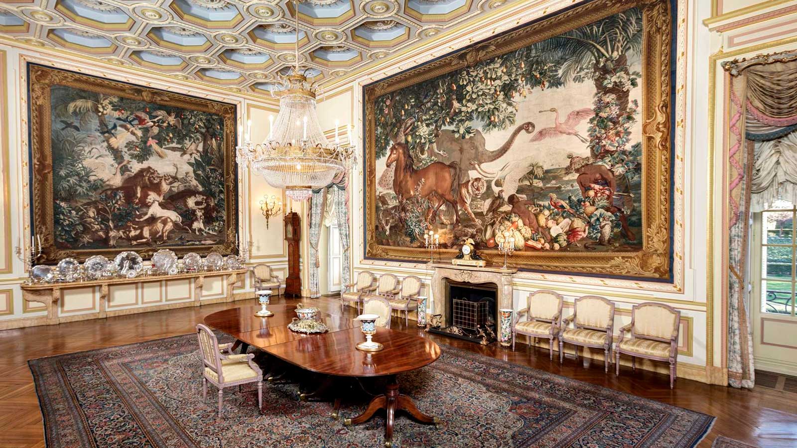 Salón histórico de un palacio de Madrid con grandes tapices, lámpara de cristal y mobiliario clásico.