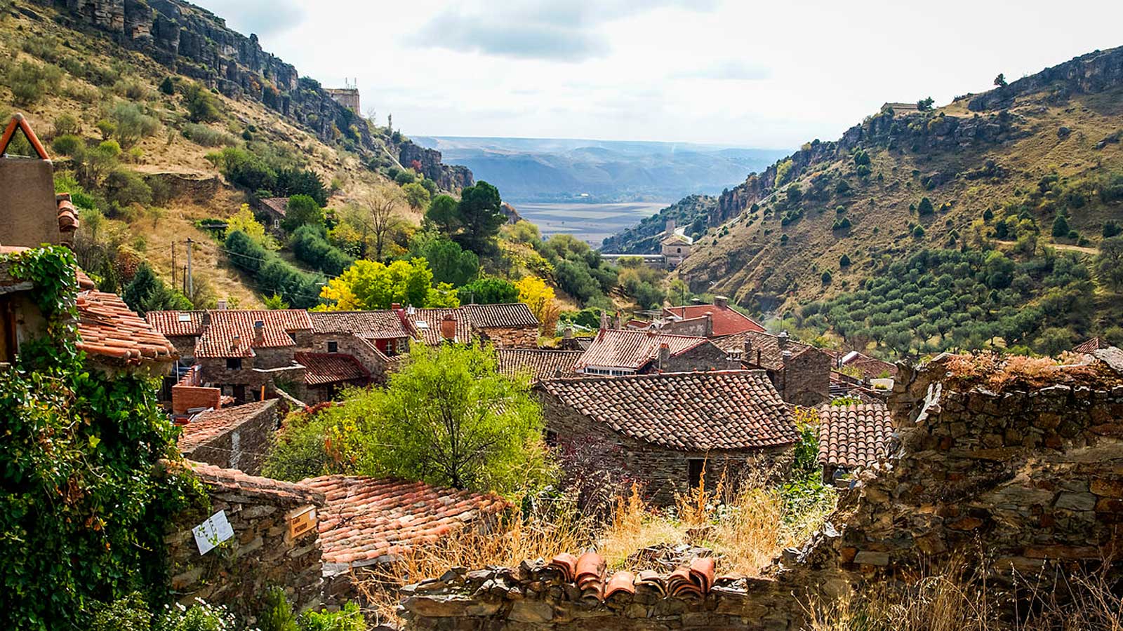 Vista panorámica de Patones de Arriba, con casas de piedra y tejados tradicionales entre montañas de Madrid