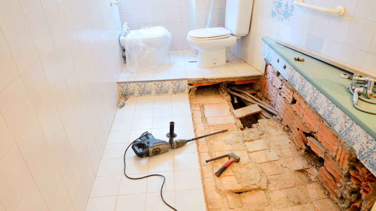 Baño de una vivienda con el suelo levantado, tuberías a la vista y una reforma sin terminar.