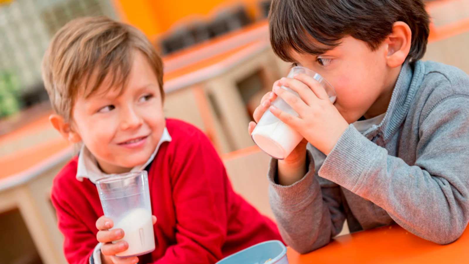 Dos niños beben leche durante una actividad escolar.