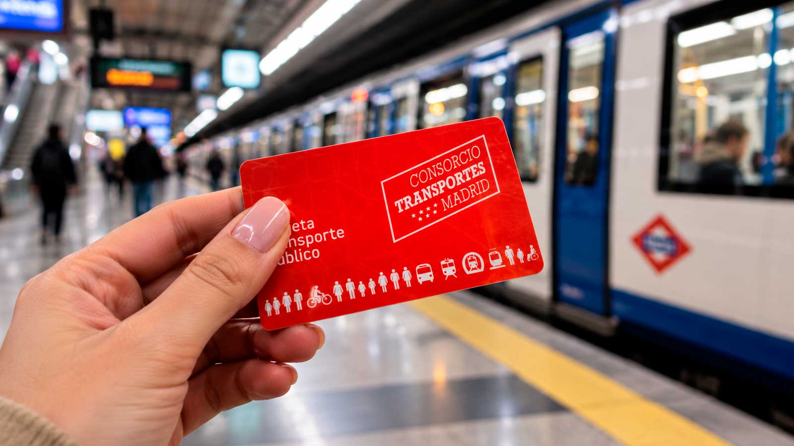 Una mujer sostiene la tarjeta de transporte público de Madrid frente a un vagón de Metro en una estación.