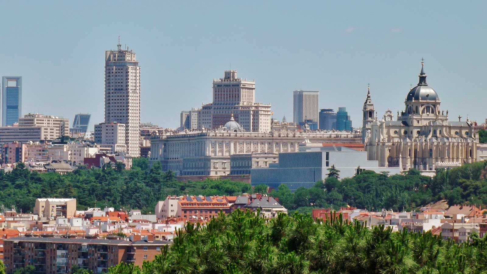 Vista panorámica de Madrid con el Palacio Real y la Catedral de la Almudena bajo un cielo despejado.