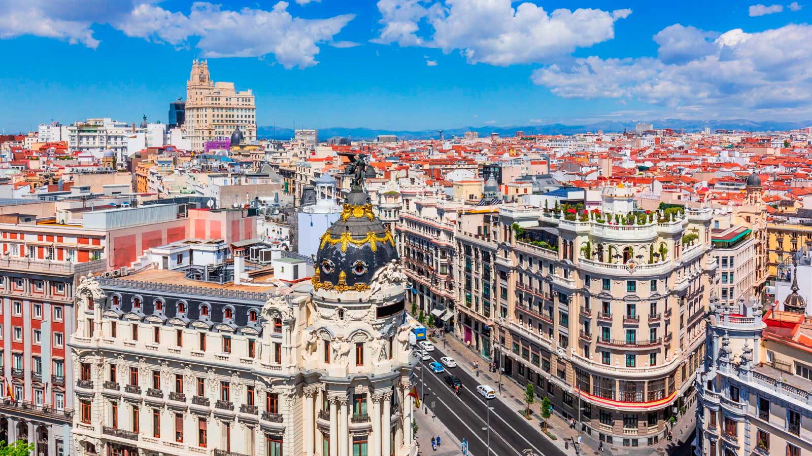 Vista panorámica de la Gran Vía de Madrid con cielo azul y nubes durante una jornada soleada.