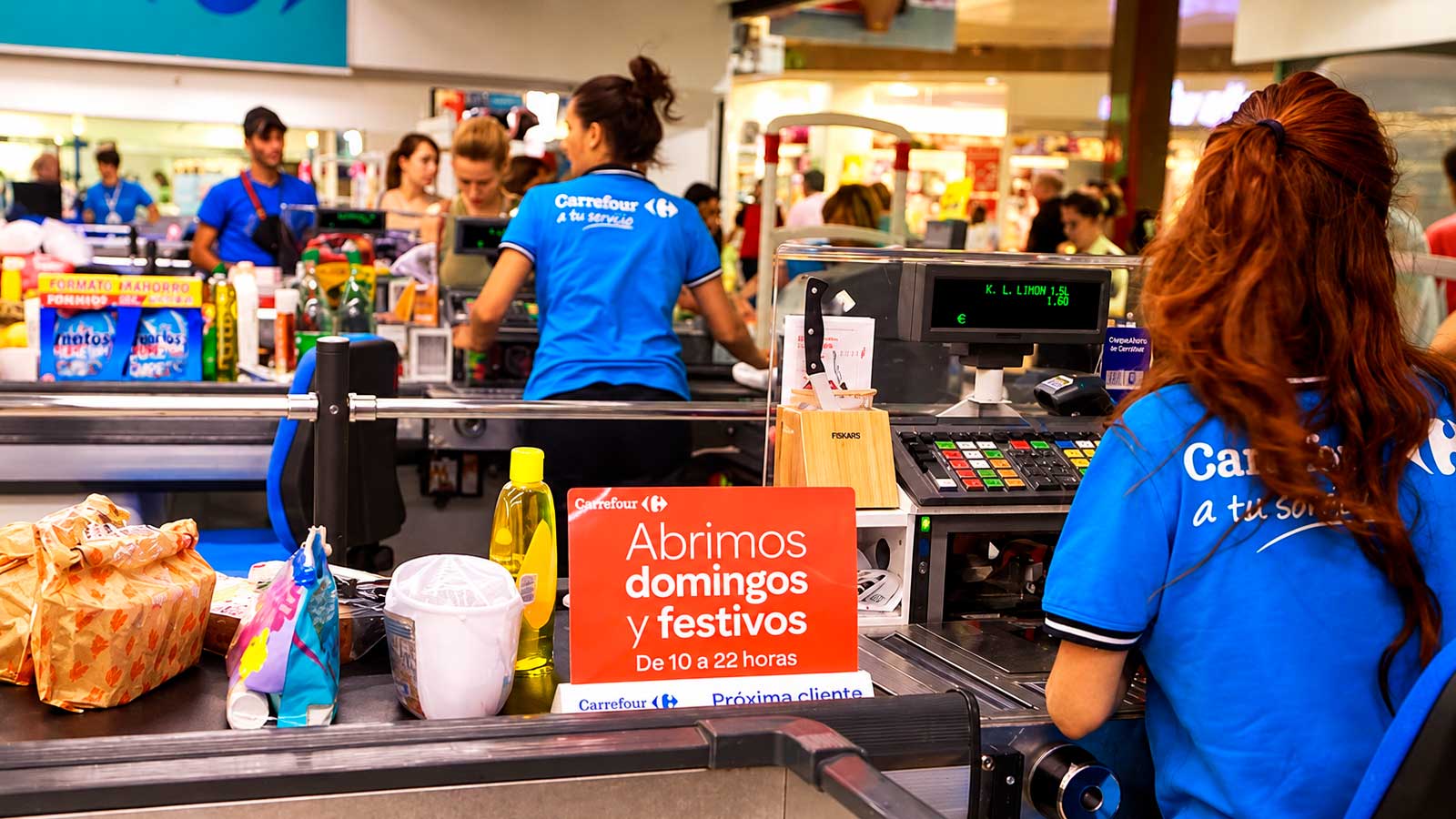 Trabajadoras de Carrefour atendiendo las cajas de un supermercado abierto en domingos y festivos.